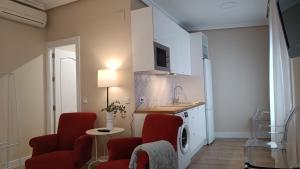 a living room with red chairs and a kitchen at Ciudad del Encaje 1 in Almagro