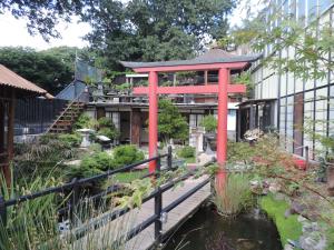 a garden with a red structure next to a pond at Zen Guest House - Museu do Bonsai in Sintra