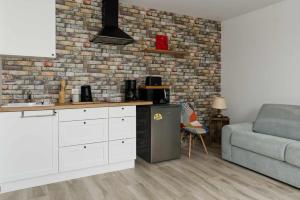 a kitchen with a refrigerator and a brick wall at L'atelier in Chambourg-sur-Indre