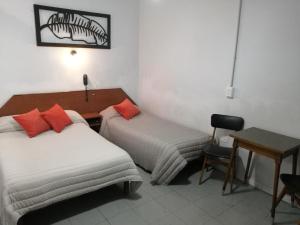 a room with two beds and a table and a desk at Suite en Hotel Omega Palermo in Buenos Aires