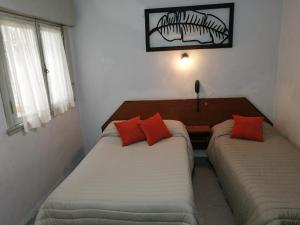 two beds with red pillows in a room at Suite en Hotel Omega Palermo in Buenos Aires