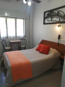 a bedroom with a large bed with two red pillows at Suite en Hotel Omega Palermo in Buenos Aires