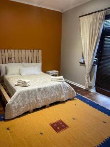 1 dormitorio con 1 cama con alfombra en el suelo en Fun-filled, cosy family home, en Gqeberha