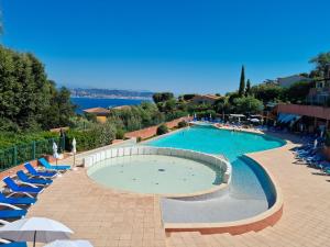 uma grande piscina com cadeiras azuis e guarda-sóis em Ravissant T2 vue mer et massif - Les Clés de L´Estérel em Théoule-sur-Mer