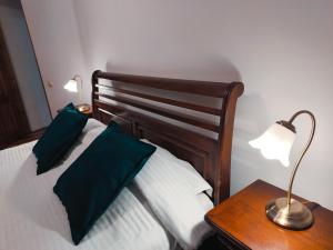 a bed with two green pillows and a table with a lamp at Old Town Studio - Victoriei 2 in Bucharest