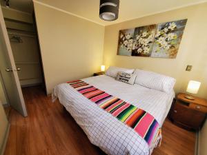 ein Schlafzimmer mit einem Bett mit einer bunten Decke darauf in der Unterkunft Encantador Metro Central in Santiago