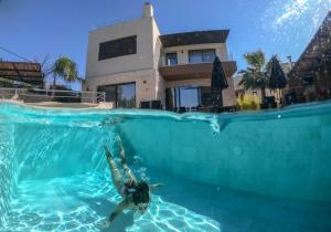 a person swimming in a swimming pool in front of a house at Almi-Cove Hilltop Villas in Almyrida