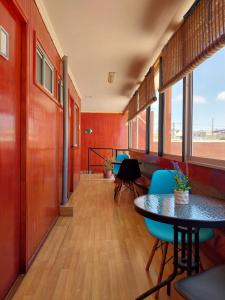 un couloir avec des tables et des chaises dans une chambre aux murs rouges dans l'établissement Hostal Jardín del Desierto, à Caldera