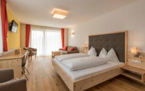 ein Schlafzimmer mit einem großen Bett und ein Wohnzimmer in der Unterkunft Hotel Schmiedhof in Meransen