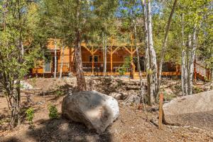 una casa nel bosco con un albero e una roccia di Eagle Creek Lodge a Big Bear Lake