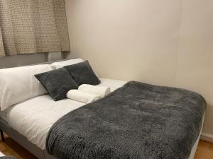 a white bed with two pillows and a gray blanket at Walk to Lcy Airport Excel Dlr 1Br Flat in London