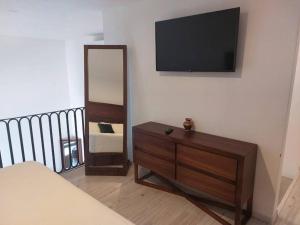 ein Schlafzimmer mit einer Kommode, einem Spiegel und einem TV in der Unterkunft Casa Monarcas - Eleonor (with AC) in Guadalajara