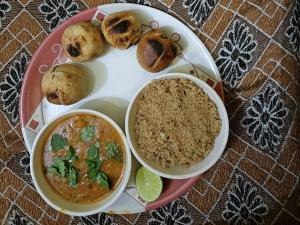 a plate of food with a bowl of soup and biscuits at Red king home stay in Bikaner +11 photos