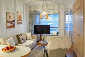 un salon avec un canapé et une télévision dans l'établissement Vasko luxurious suites, Luppo, à Rovaniemi