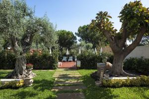ジャルディーニ・ナクソスにあるVilla Collinaの二本の木と石の小道がある庭園