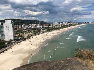 a beach with people in the water and buildings at Apartamento Pitangueiras in Guarujá