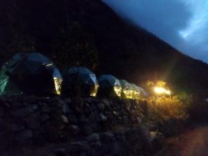 un grupo de tiendas de campaña en una pared de piedra por la noche en Sky Lodge Domes Chaullay en Colcapampa