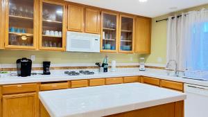 een keuken met houten kasten en witte aanrechtbladen bij Spacious home sleeps 14 with pool table in Las Vegas