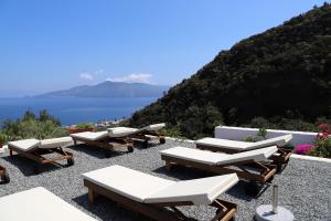 un gruppo di sedie a sdraio e tavoli in cima a una collina di B&B Sunrise a Santa Marina Salina