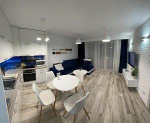 a kitchen and a living room with a table and chairs at Apartament Faleza16 in Rewal