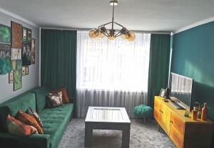 a living room with a green couch and a table at Przystanek Krupówki in Zakopane