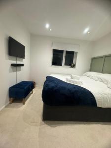 a bedroom with a large bed and a blue ottoman at Modern 1 Bedroom House in Biggleswade in Biggleswade