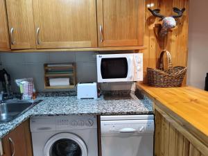 a kitchen with a washing machine and a microwave at Cerler- Aigualluts-Pirineo en familia in Cerler