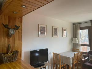 a living room with a table and a television at Cerler- Aigualluts-Pirineo en familia in Cerler