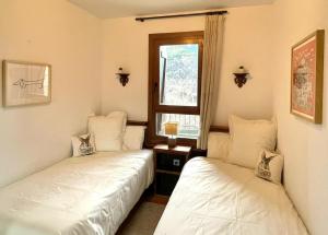 two beds in a room with a window at Inmocyma Cerler- Aigualluts-Pirineo en familia in Cerler