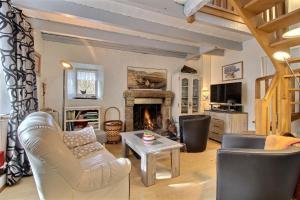 a living room with white furniture and a fireplace at Le petit moulin kersigalec in Canihuel