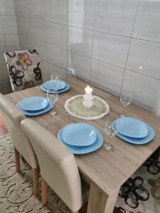 een houten tafel met blauwe platen en een kaars erop bij Apartman Aki in Pirot