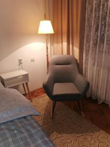 a room with a chair and a lamp and a bed at Apartman Aki in Pirot