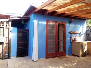 ein blaues Haus mit einer roten Tür und einer Küche in der Unterkunft Finca Caboquitos in Garafía