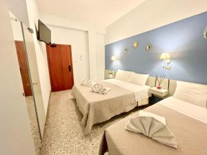 a hotel room with two beds and a blue wall at Hotel Alfa - SPIAGGIA INCLUSA con Formula All Inclusive 7 notti in Rimini