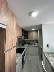 una cocina con encimeras blancas y armarios de madera en Excelente Depto Torre Leloir by Inside en Villa Marini