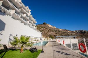 a building with a pool and a mountain in the background at Sky Marina Luxury in La Herradura