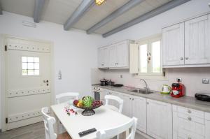 a kitchen with white cabinets and a table with a bowl of fruit at My Villa in Agios Georgios