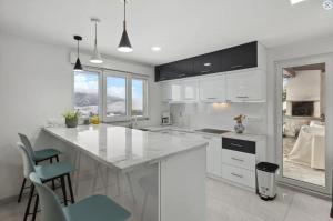 una cucina bianca con un grande bancone bianco e sedie di Magnificent mountain home - 756 a Crans-Montana