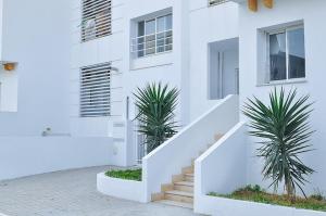 a white building with stairs and two palm trees at Appartement Cosy au calme in Ben Arous