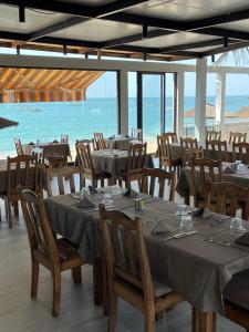 uma sala de jantar com mesas e cadeiras e o oceano em CASA COCO II em Nianing