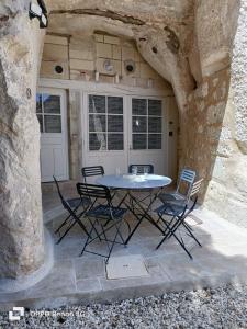 a patio with a table and chairs under a stone wall at La troglodyte fantastique Lochoise in Loches