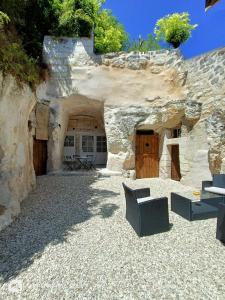 a patio with two chairs and a stone building at La troglodyte fantastique Lochoise in Loches