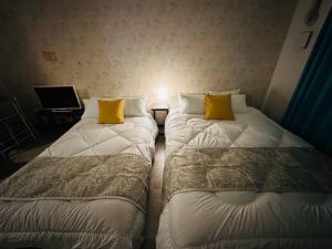 two beds with yellow pillows in a room at 302 黒門市場1分!道頓堀まで徒歩8分!心斎橋まで徒歩9分 in Osaka