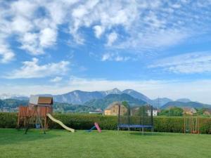 a playground with play equipment in a field with mountains at Bungalows Bergpanorama in Sankt Kanzian