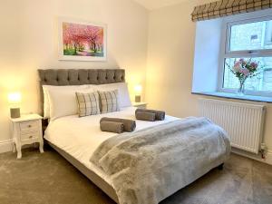 a bedroom with a large bed with two pillows on it at Blossom Tree Cottage in Barnoldswick