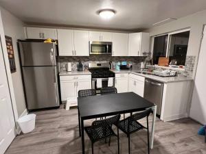 a kitchen with white cabinets and a black table and chairs at 2 bedroom in Denver, Centralized in Denver