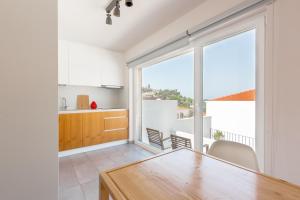 a kitchen with white cabinets and a large window at Retiro do Castelo in Óbidos