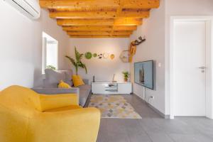 een woonkamer met een gele stoel en een tv bij Retiro do Castelo in Óbidos
