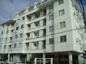 un gran edificio blanco con un coche aparcado delante de él en Apto de dois quartos com uma suíte, en Palhoça