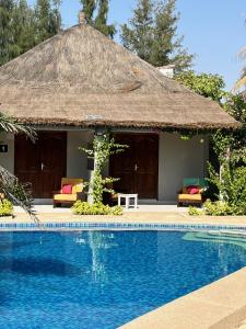 ein Resort mit einem Pool vor einer Hütte in der Unterkunft CASA COCO II in Nianing